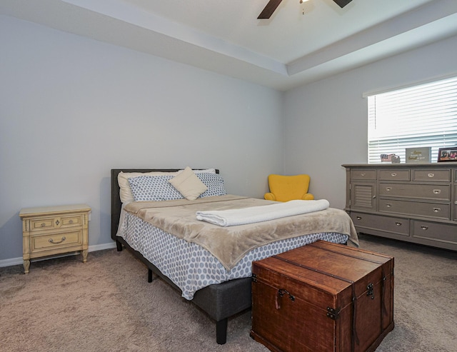 carpeted bedroom featuring ceiling fan and a tray ceiling