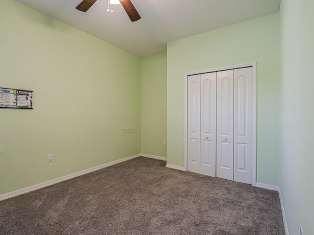 unfurnished bedroom with dark colored carpet, ceiling fan, and a closet