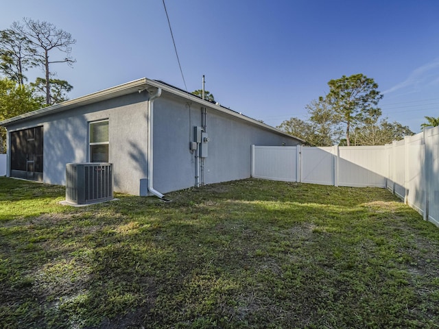 rear view of house featuring a yard and central air condition unit