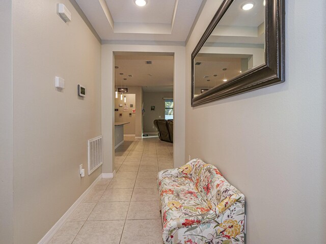 hallway featuring light tile patterned floors and a raised ceiling