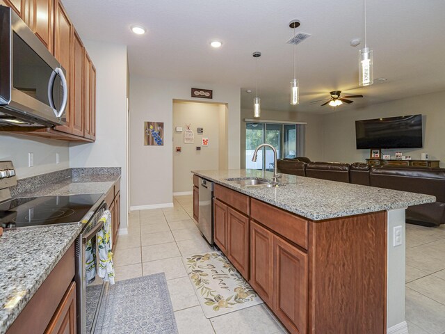 kitchen featuring sink, hanging light fixtures, light tile patterned floors, appliances with stainless steel finishes, and light stone countertops