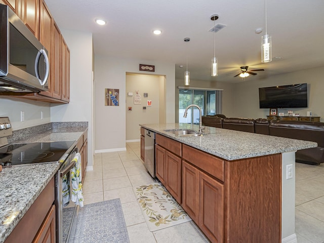 kitchen featuring a kitchen island with sink, sink, decorative light fixtures, and stainless steel appliances