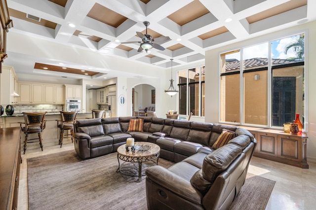 living room with a high ceiling, coffered ceiling, ceiling fan, and beam ceiling