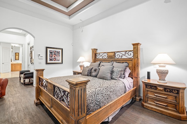 bedroom with dark hardwood / wood-style floors and a raised ceiling