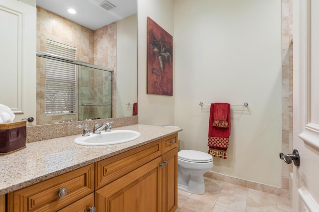 bathroom featuring a shower with door, vanity, tile patterned flooring, and toilet