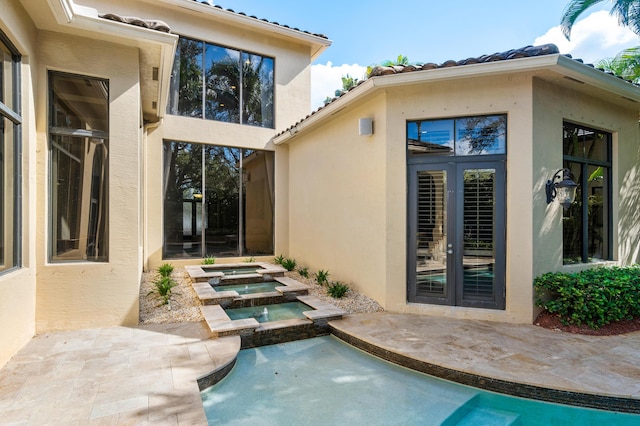 back of house featuring french doors, an in ground hot tub, and a patio area