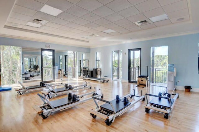 workout area featuring crown molding, a drop ceiling, light wood-type flooring, and a tray ceiling