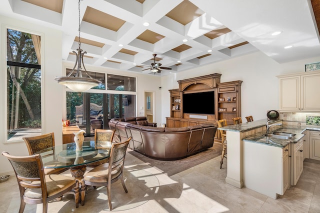 dining area featuring beamed ceiling, coffered ceiling, sink, and a towering ceiling