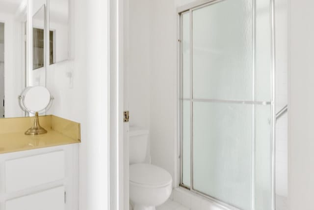 bathroom with toilet, a stall shower, and vanity