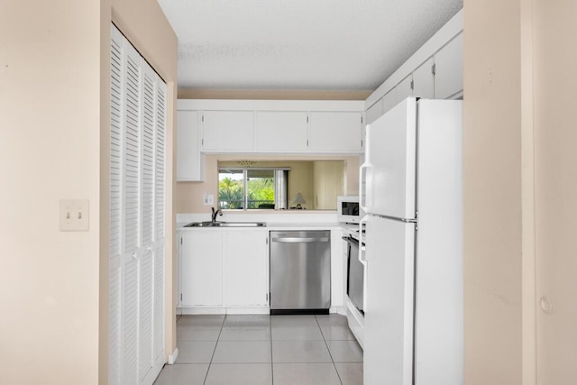 kitchen featuring white appliances, light tile patterned floors, sink, and white cabinets