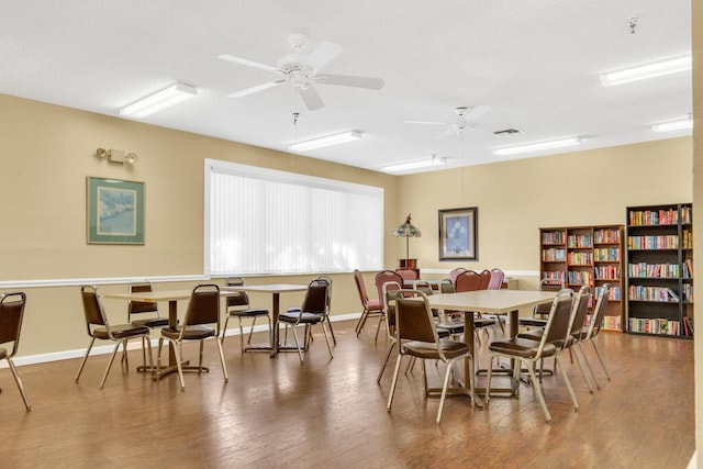 dining room with visible vents, ceiling fan, baseboards, and wood finished floors