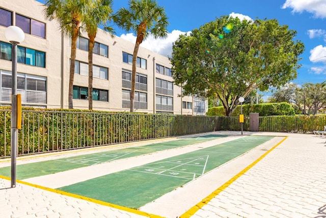 view of community featuring fence and shuffleboard