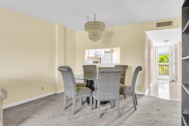 dining room with carpet floors, an inviting chandelier, visible vents, and a textured ceiling