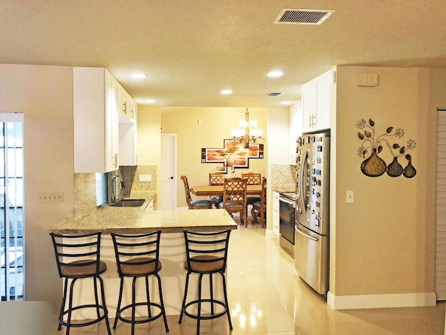 kitchen with sink, white cabinetry, kitchen peninsula, stainless steel appliances, and decorative backsplash