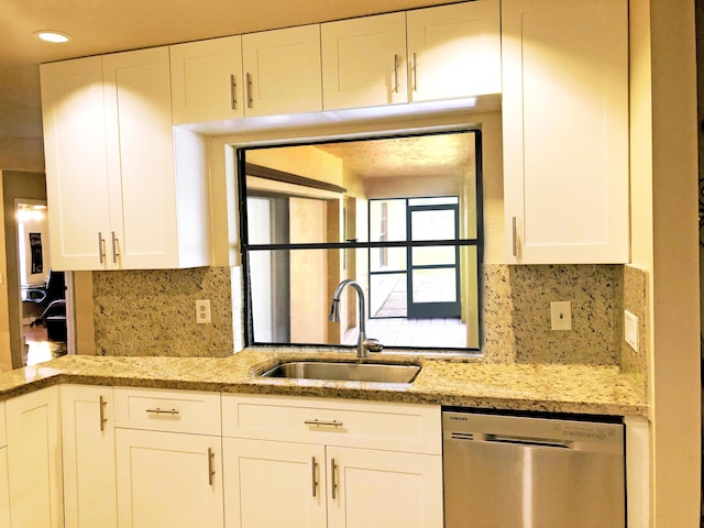 kitchen featuring sink, stainless steel dishwasher, white cabinets, and light stone counters