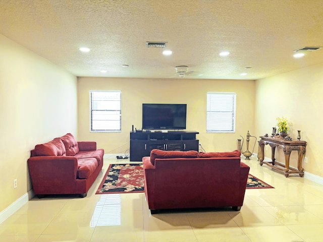 living room featuring ceiling fan, light tile patterned floors, and a textured ceiling