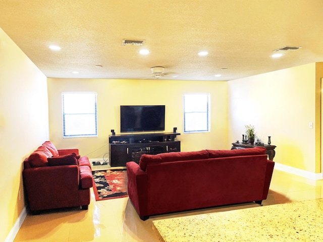 living room featuring ceiling fan and a textured ceiling