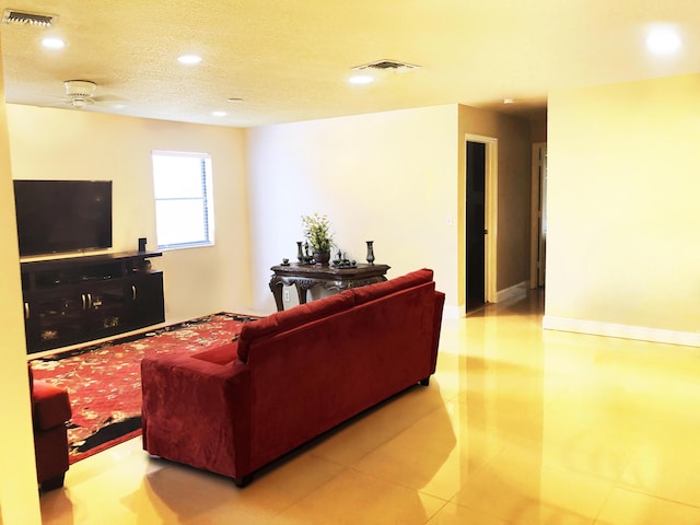 living room featuring ceiling fan, a textured ceiling, and light tile patterned floors