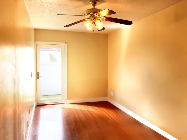 empty room featuring ceiling fan, hardwood / wood-style floors, and a textured ceiling