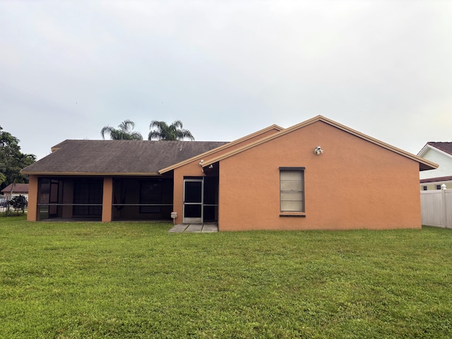 back of house featuring a sunroom and a lawn