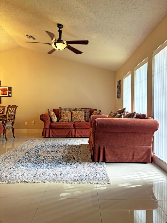 living room with vaulted ceiling, ceiling fan, and a textured ceiling