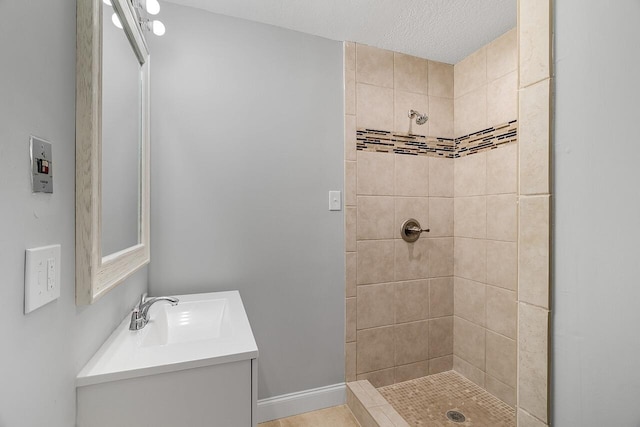 bathroom featuring tiled shower, vanity, and a textured ceiling