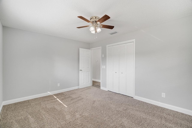 unfurnished bedroom featuring ceiling fan, carpet flooring, a closet, and a textured ceiling