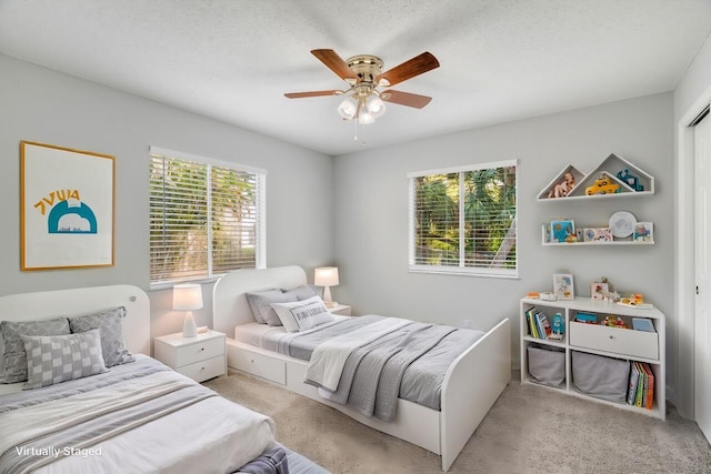 carpeted bedroom featuring multiple windows, ceiling fan, and a textured ceiling