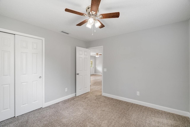 unfurnished bedroom with ceiling fan, a closet, a textured ceiling, and carpet