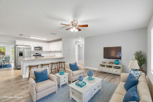 living room with sink, light hardwood / wood-style flooring, and ceiling fan