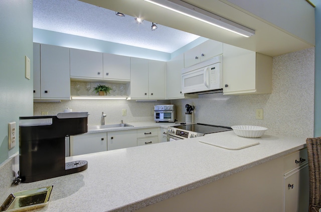 kitchen with backsplash, sink, stainless steel range with electric cooktop, and white cabinets