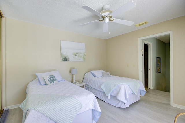 bedroom with ceiling fan, light hardwood / wood-style floors, and a textured ceiling