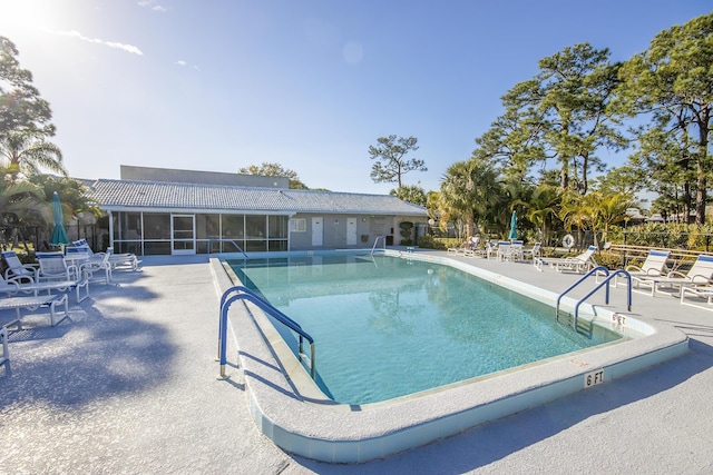 view of swimming pool with a sunroom and a patio area