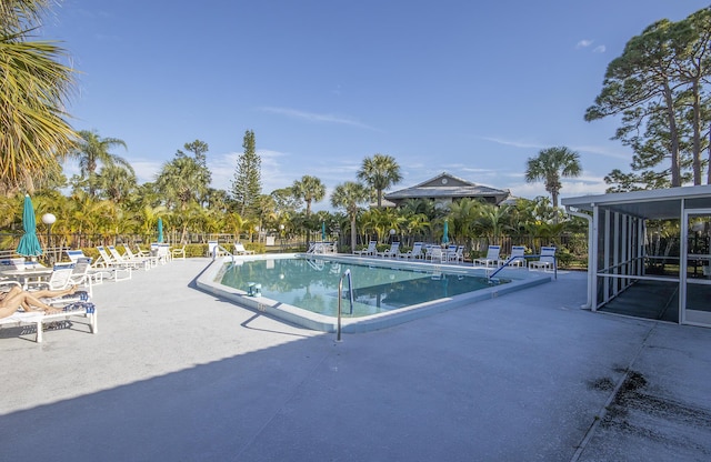 view of swimming pool featuring a patio area and a sunroom