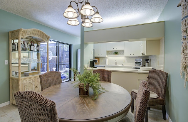 dining space with sink, a notable chandelier, and a textured ceiling