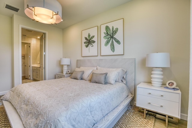 bedroom featuring ensuite bathroom and light wood-type flooring