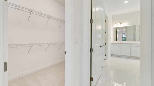 walk in closet with sink and light colored carpet