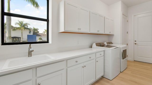 clothes washing area with cabinets, plenty of natural light, sink, and washer and clothes dryer