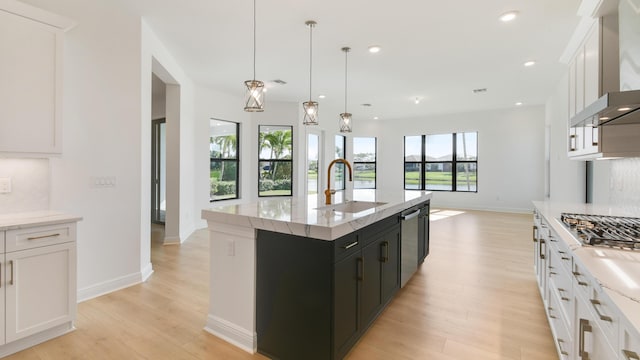 kitchen featuring white cabinetry, hanging light fixtures, sink, and a center island with sink