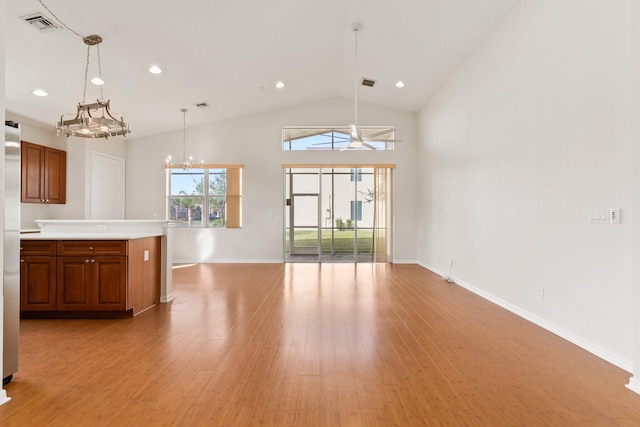 kitchen with an inviting chandelier, pendant lighting, high vaulted ceiling, and light hardwood / wood-style flooring