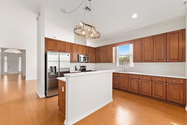 kitchen featuring sink, decorative light fixtures, a center island, light hardwood / wood-style flooring, and appliances with stainless steel finishes