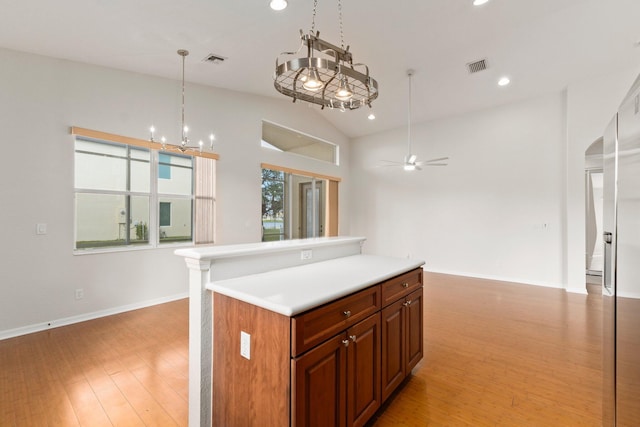 kitchen with vaulted ceiling, hanging light fixtures, light hardwood / wood-style flooring, a kitchen island, and ceiling fan