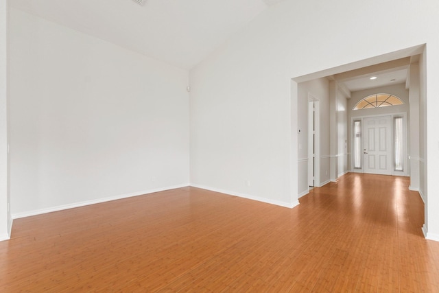 spare room with wood-type flooring and high vaulted ceiling