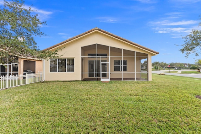 rear view of house with a yard and a sunroom