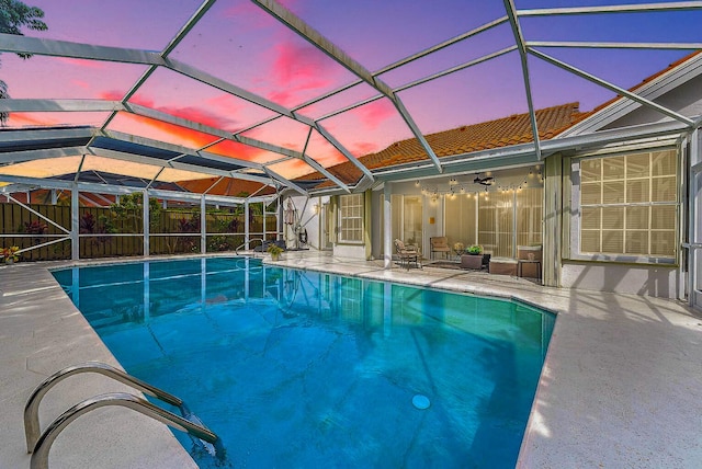 view of swimming pool with glass enclosure, a patio, a fenced in pool, a ceiling fan, and fence