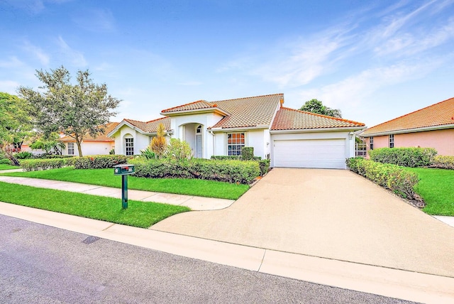 mediterranean / spanish home with concrete driveway, a tile roof, a front yard, stucco siding, and a garage