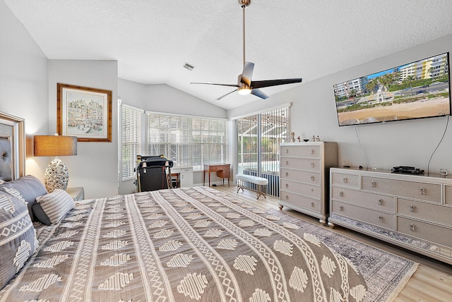 bedroom featuring visible vents, ceiling fan, lofted ceiling, wood finished floors, and a textured ceiling