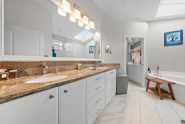 full bath featuring walk in shower, lofted ceiling with skylight, a bath, marble finish floor, and a sink