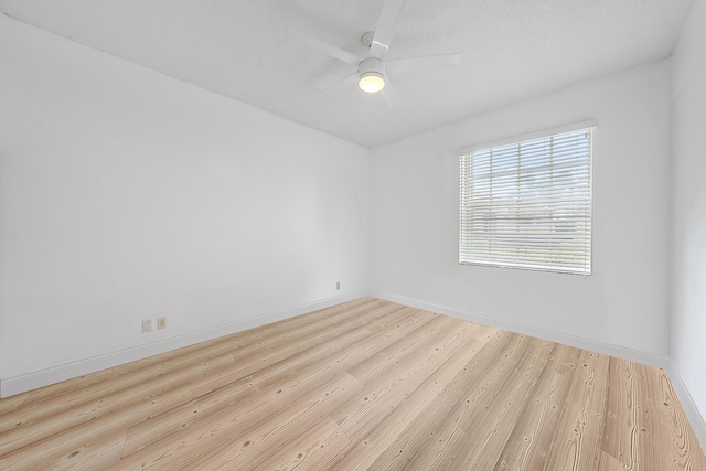 empty room with baseboards, wood finished floors, and a ceiling fan