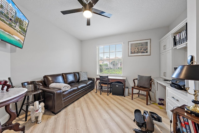 living room featuring a textured ceiling, ceiling fan, and light wood-type flooring